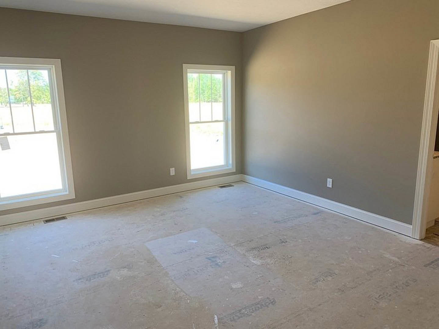 White plaster walls, window with white frame and side bars, tile flooring with visible hole, white door frame, minimal interior finishes.