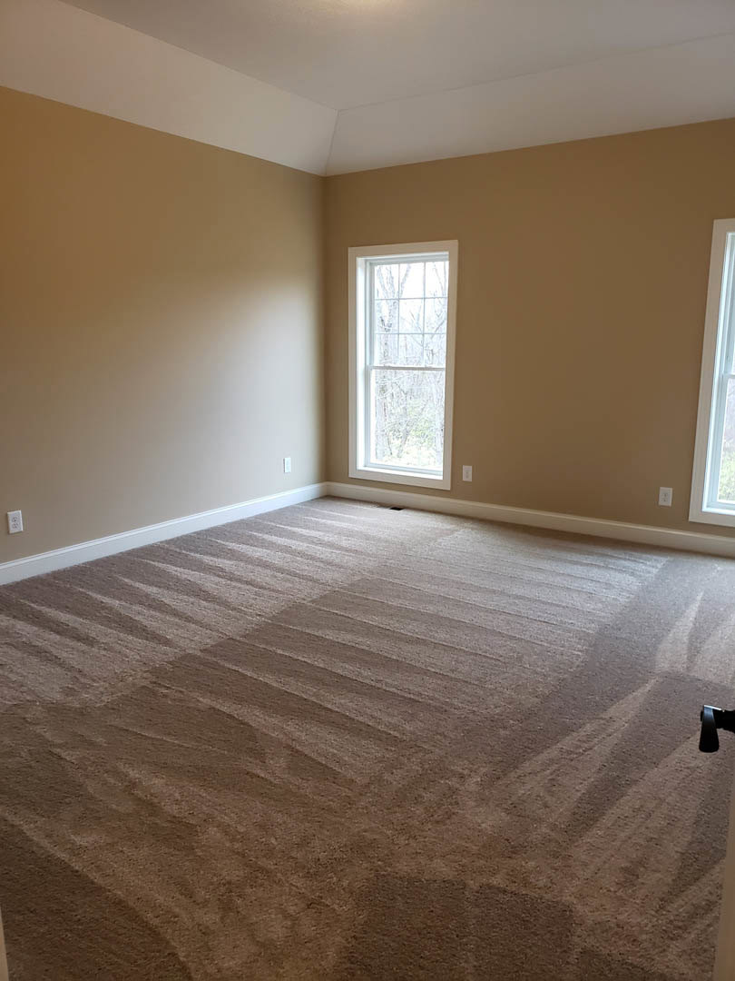 Bedroom with light carpet flooring, two white-framed windows, white walls, and a white door
