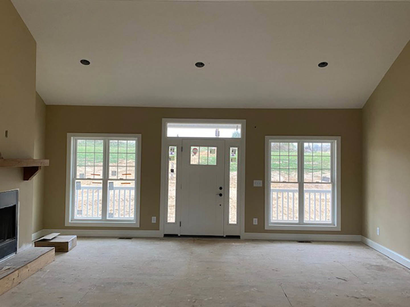 Concrete floor with close-up texture, white door featuring glass panes, white-framed windows with railing, plaster walls, and blurred desk in a monochrome interior.