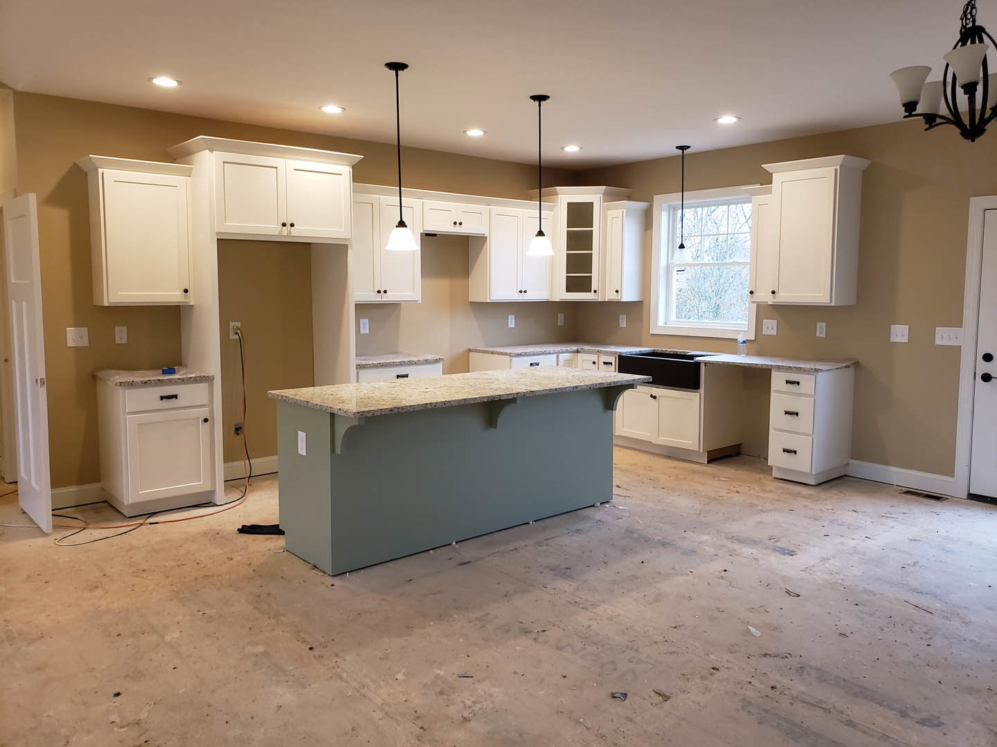 Kitchen with white shaker cabinets, marbled countertop, black cabinet handles, ceiling light fixture, and blue decorative object on counter
