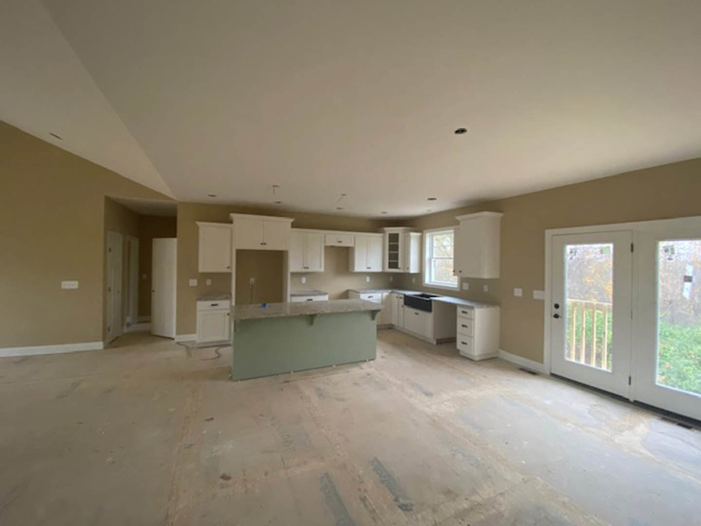 Modern kitchen with white quartz countertop, glass-paneled double doors, white cabinetry with black handles, and light-colored flooring showing visible dirt.