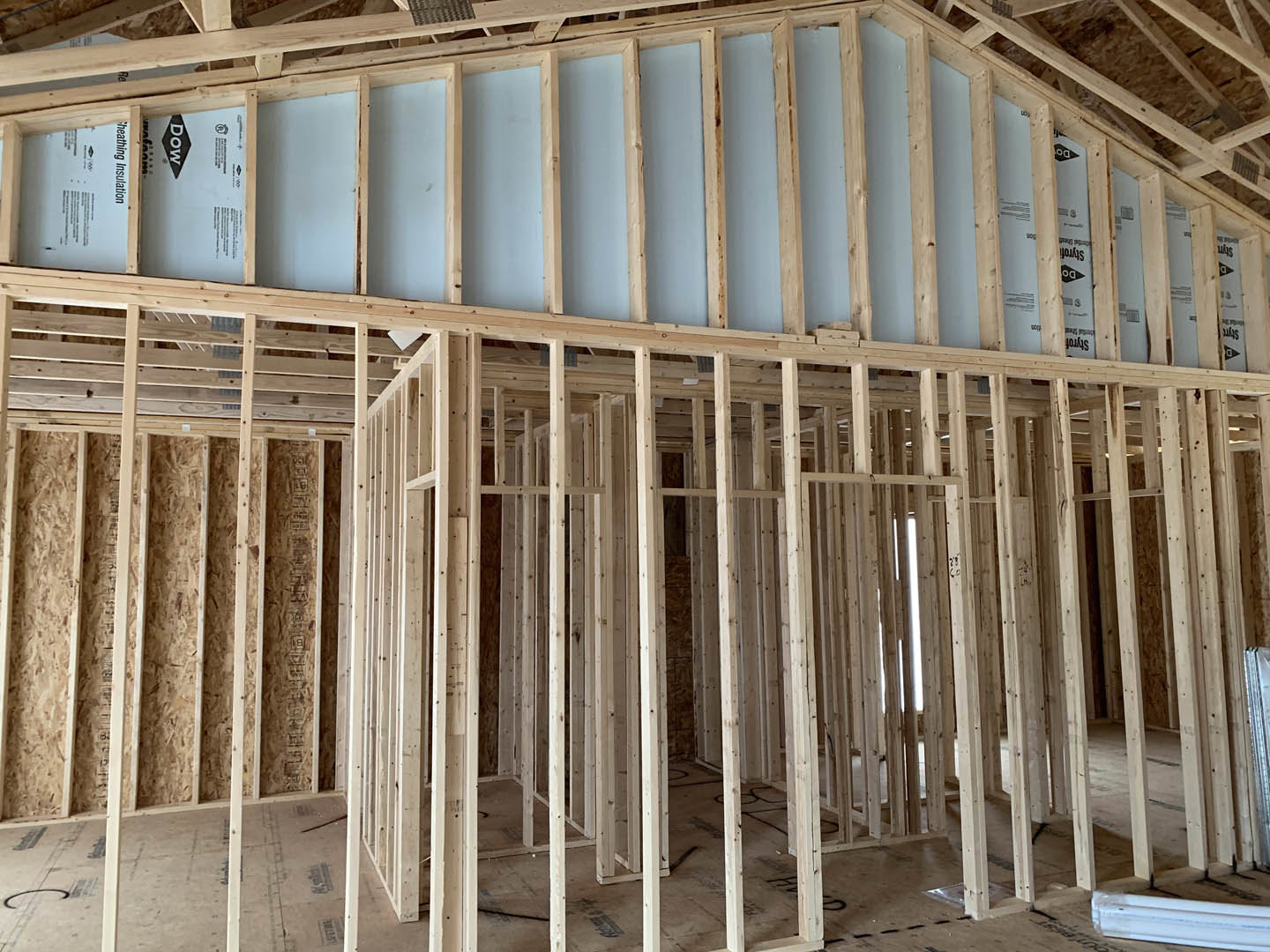 Exposed wooden beams and framing inside a partially constructed residential home, with visible lumber and insulation materials.