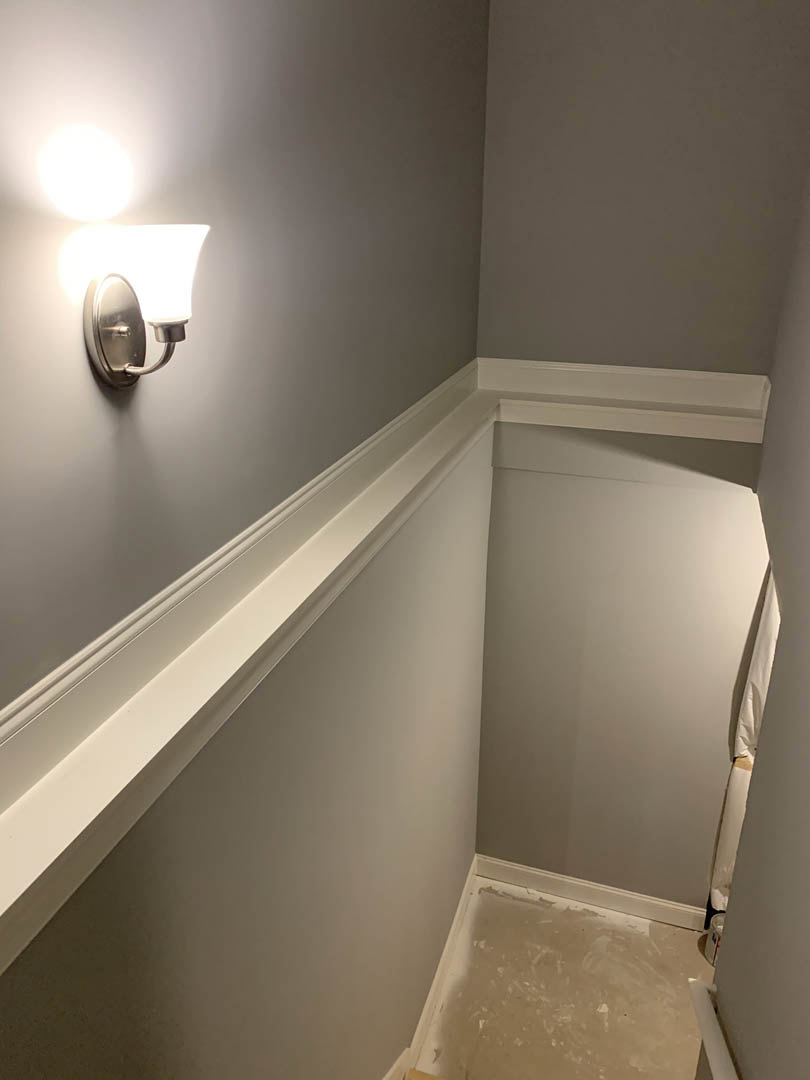 White plaster hallway with marble floor, wall-mounted light fixture, and white curtain against a smooth wall.