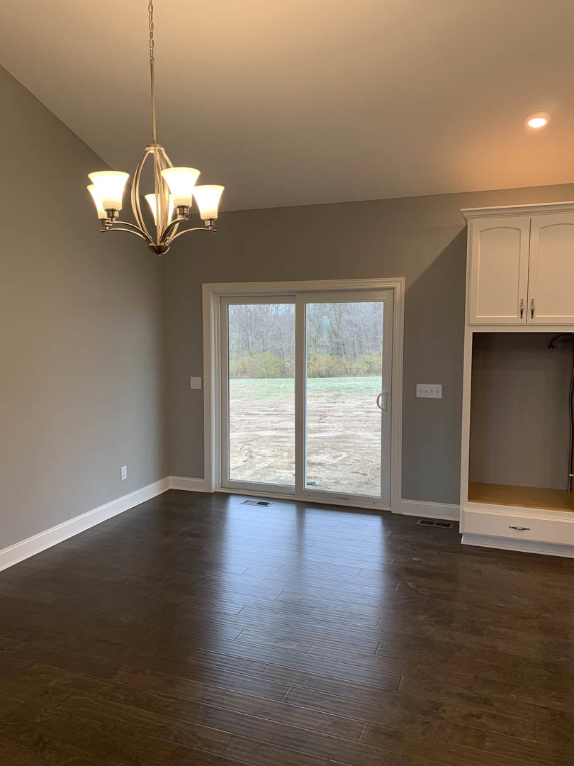 Hardwood floor room featuring a white cabinet with black handles, glass door and sliding glass door, three-light chandelier, plaster walls, and wood ceiling accents