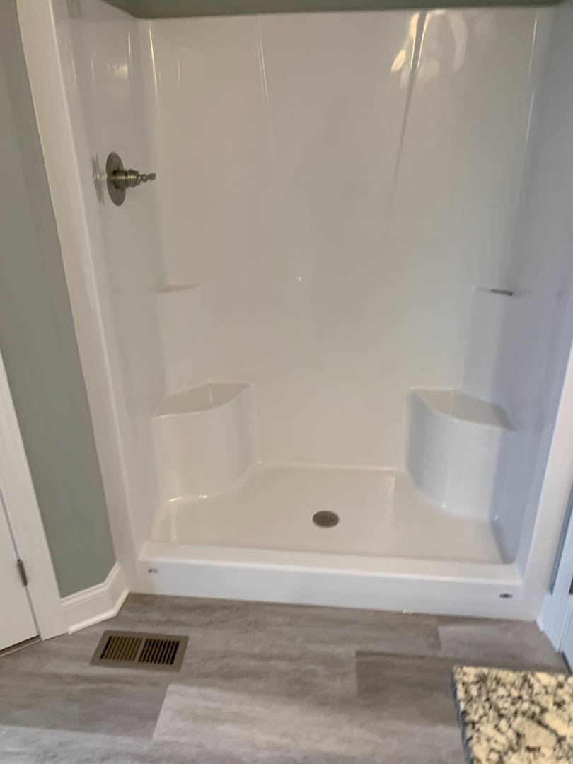 Walk-in shower with glass enclosure, marble tile walls, built-in niche, chrome plumbing fixtures, and recessed ceiling vent in modern bathroom
