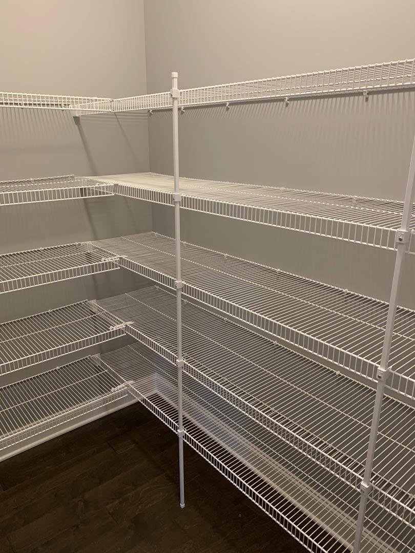 White metal wire shelving installed along a wall in an empty room with light-colored flooring