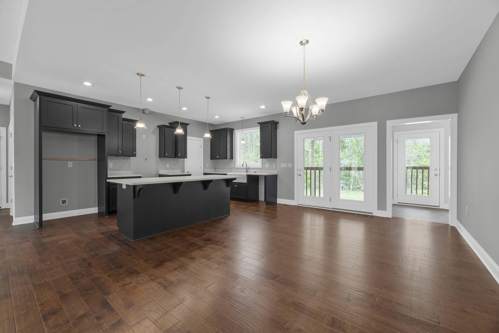 Open kitchen and dining area featuring hardwood floors, white cabinetry, black and white countertops, double glass-paneled doors, and a white door with a glass window.