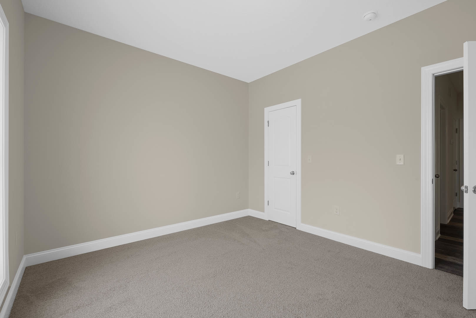 White paneled door with silver knob set in a carpeted room, light-colored walls with simple base molding