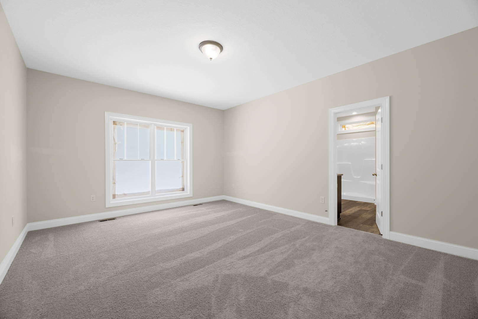 Carpeted bedroom with white closet door, large window, and ceiling light fixture