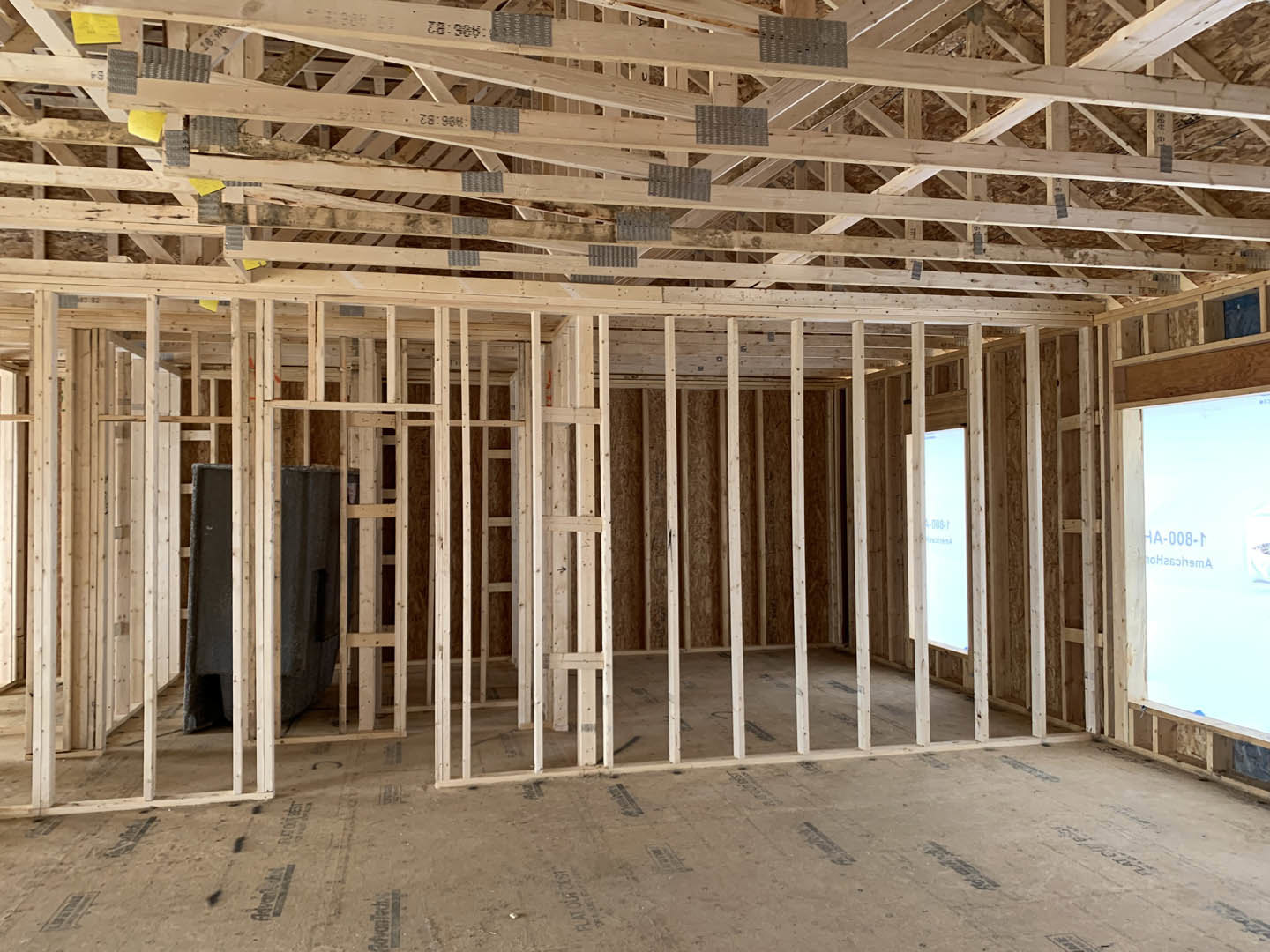 Exposed wooden beams and framing inside a house under construction, with unfinished walls and visible lumber.