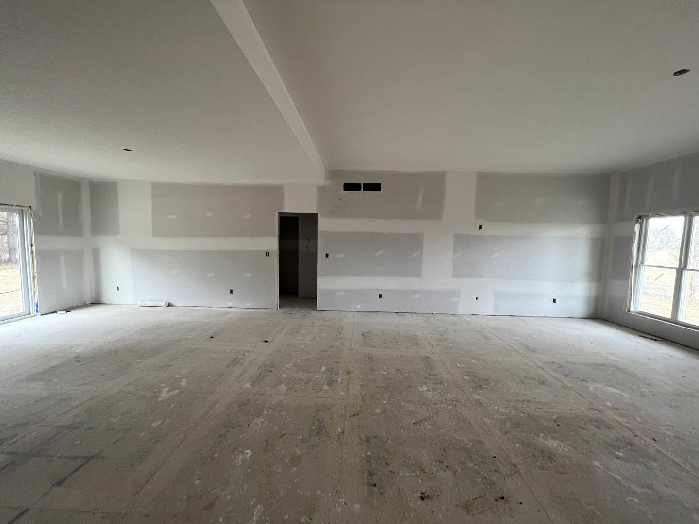 White-walled room with a white ceiling, white-framed window overlooking a field, single door, and light-colored flooring.