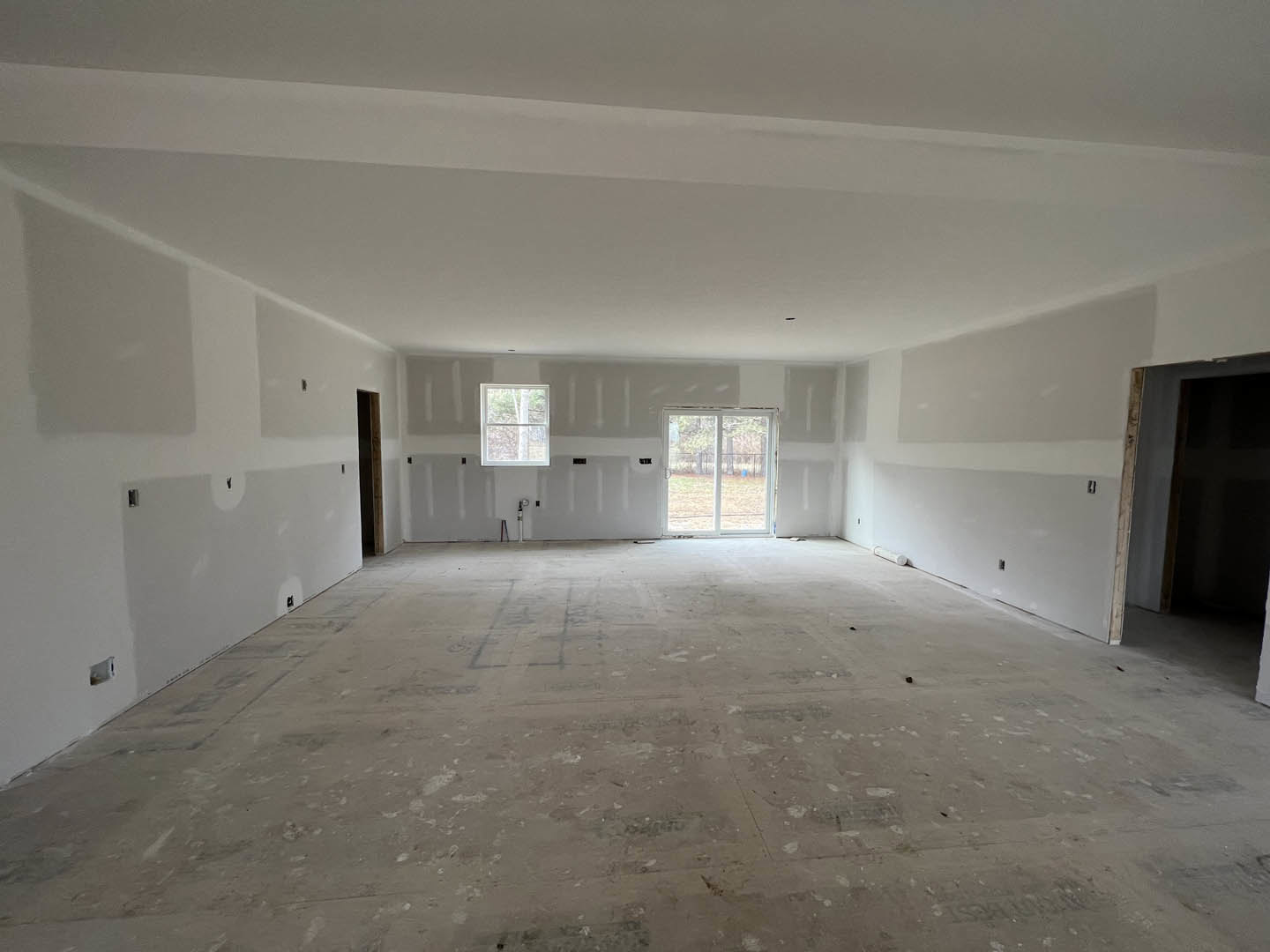 White-walled room with a sliding glass door and window featuring white frames, light-colored flooring, and plaster ceiling.