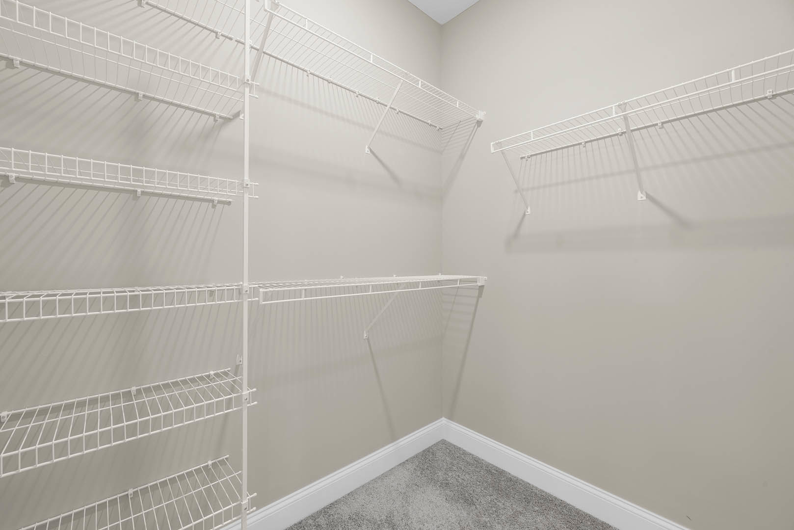 White built-in shelves mounted on a plaster wall in a bathroom, with white wire racks and carpeted flooring visible.