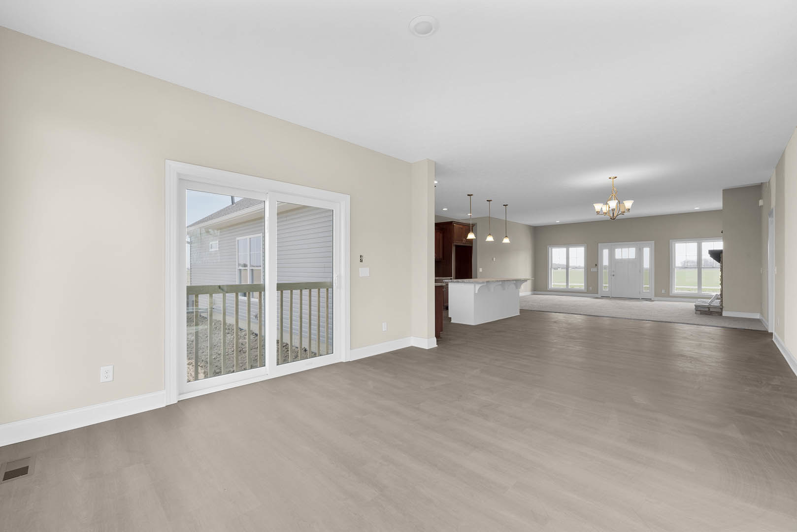 Room with wood flooring, sliding glass door opening to porch with white railing, white countertop and brown door, plaster walls and ceiling.
