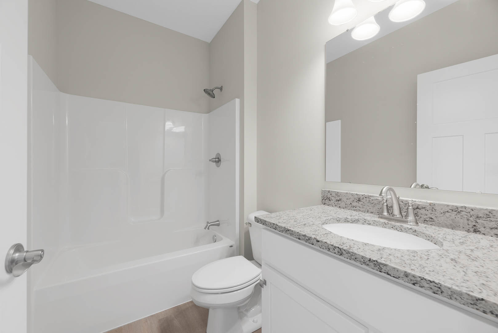 Bathroom with marbled countertop and white sink, freestanding bathtub, tiled walls, chrome fixtures, and white door visible.