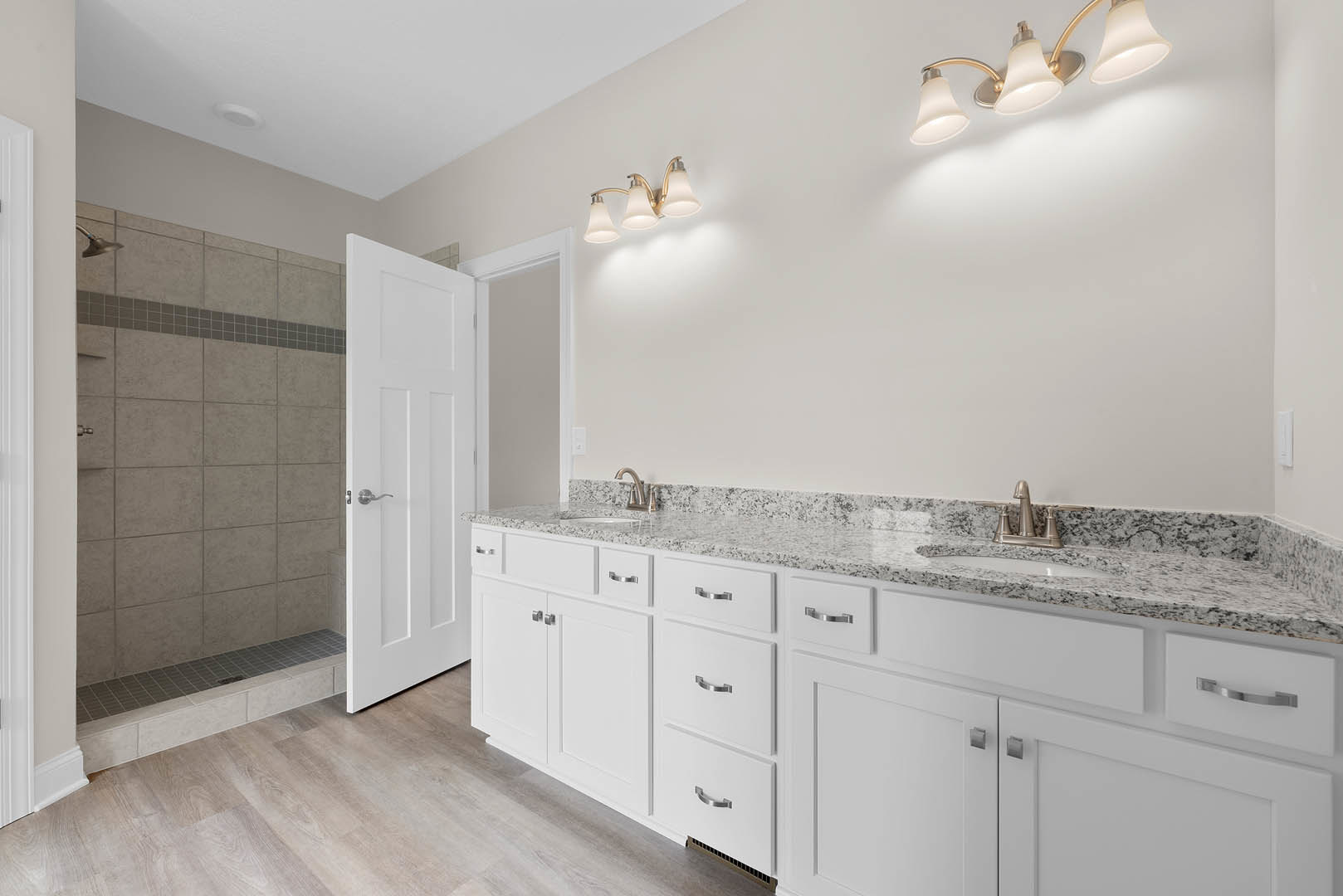 Bathroom with white cabinets, marble countertops, undermount sink, chrome faucet, and three-light fixture above mirror