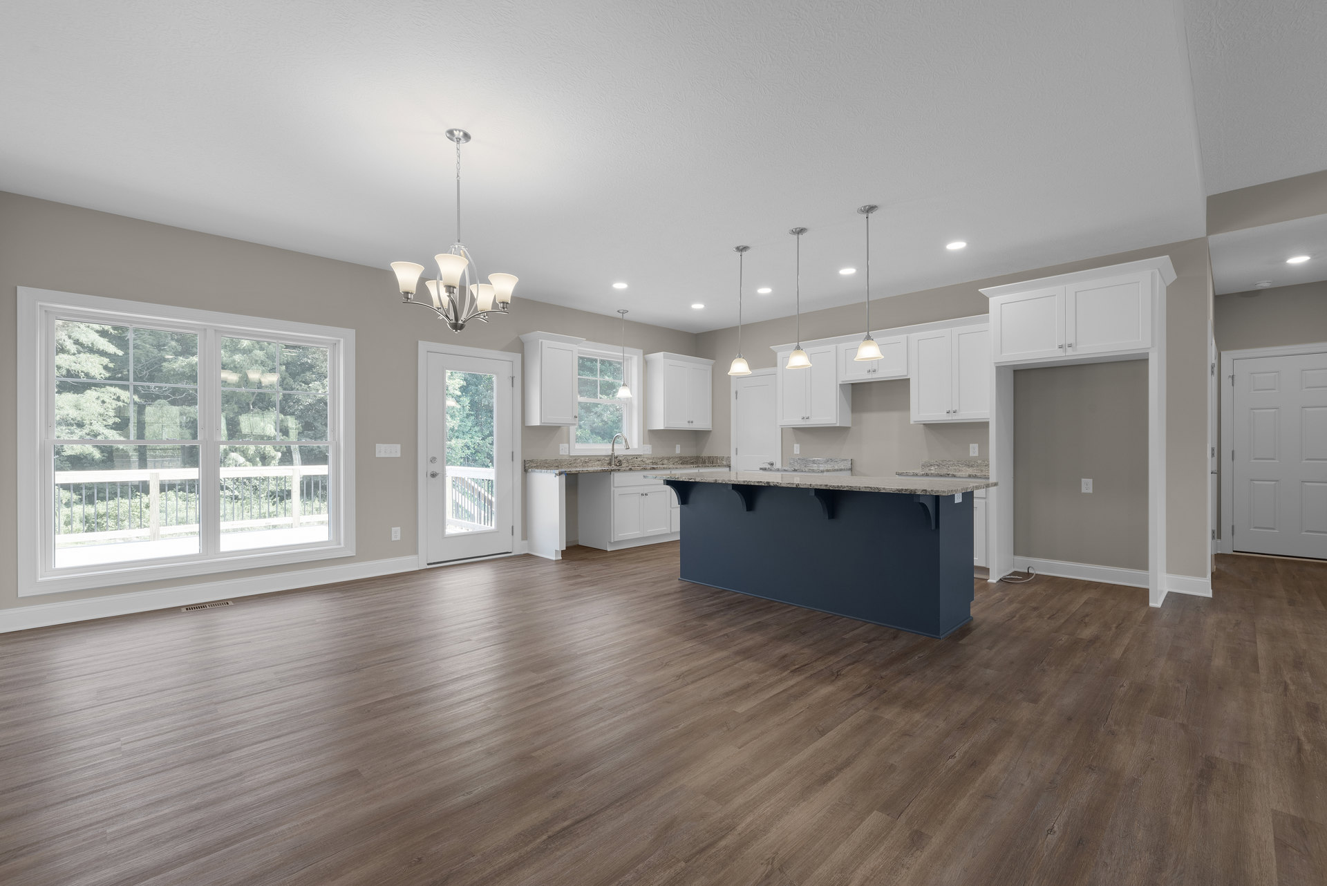 Open kitchen and dining area with hardwood flooring, white paneled doors, glass window with railing, stone countertop, and view of trees outside