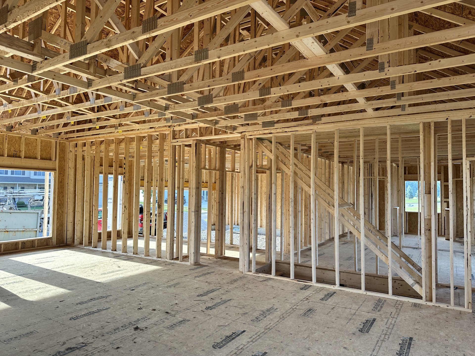 Exposed wood framing and beams during residential home construction, unfinished interior with visible structural supports and subfloor.