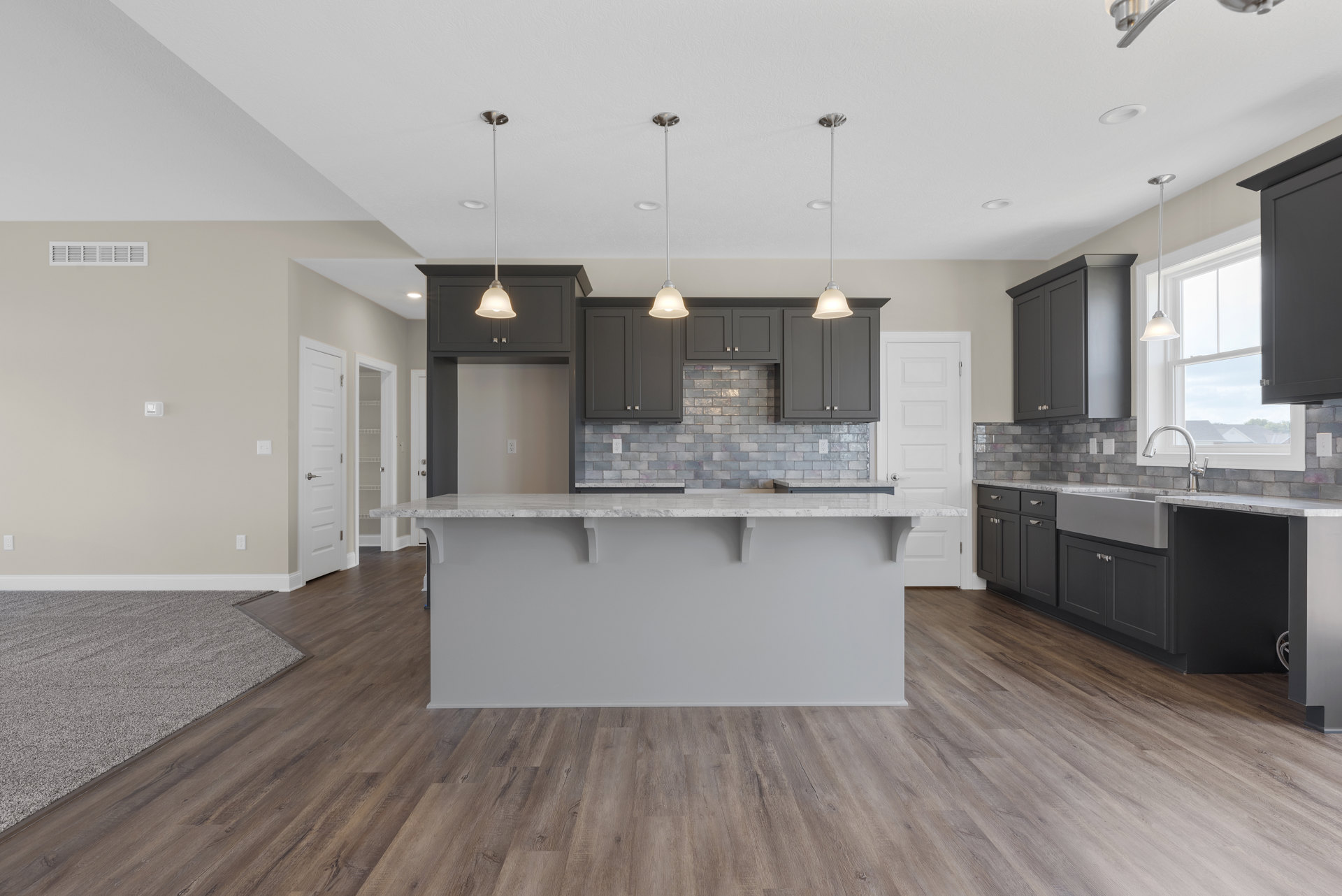 Kitchen with hardwood flooring, central island featuring stone countertop, white cabinetry, tile backsplash, open shelving above counter, recessed lighting and bell-shaped pendant