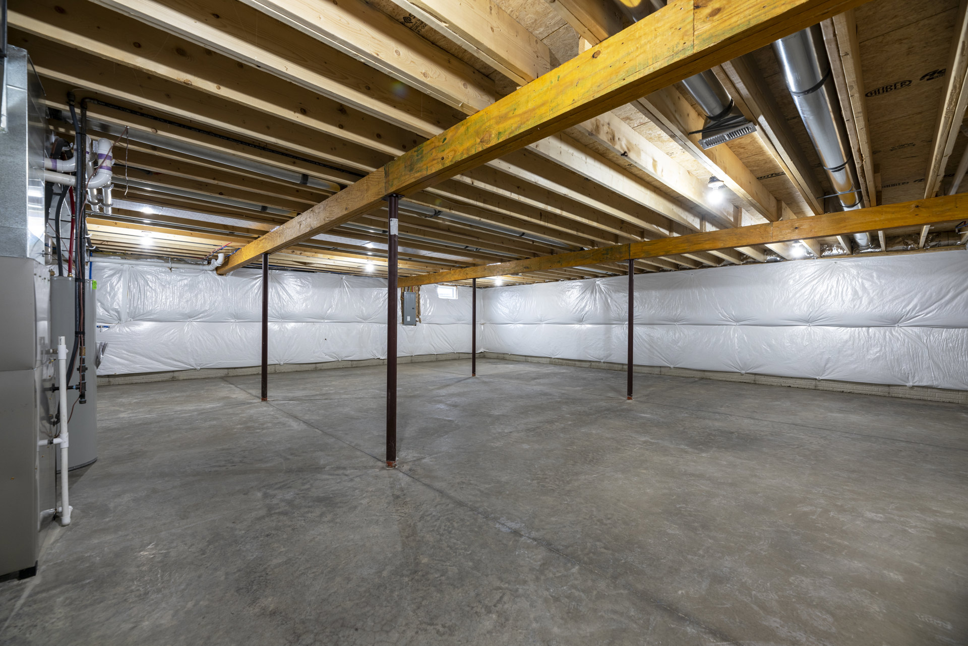 Exposed wooden ceiling beams, white plaster wall, concrete floor with steel support pole, metal pipe integrated into wood ceiling