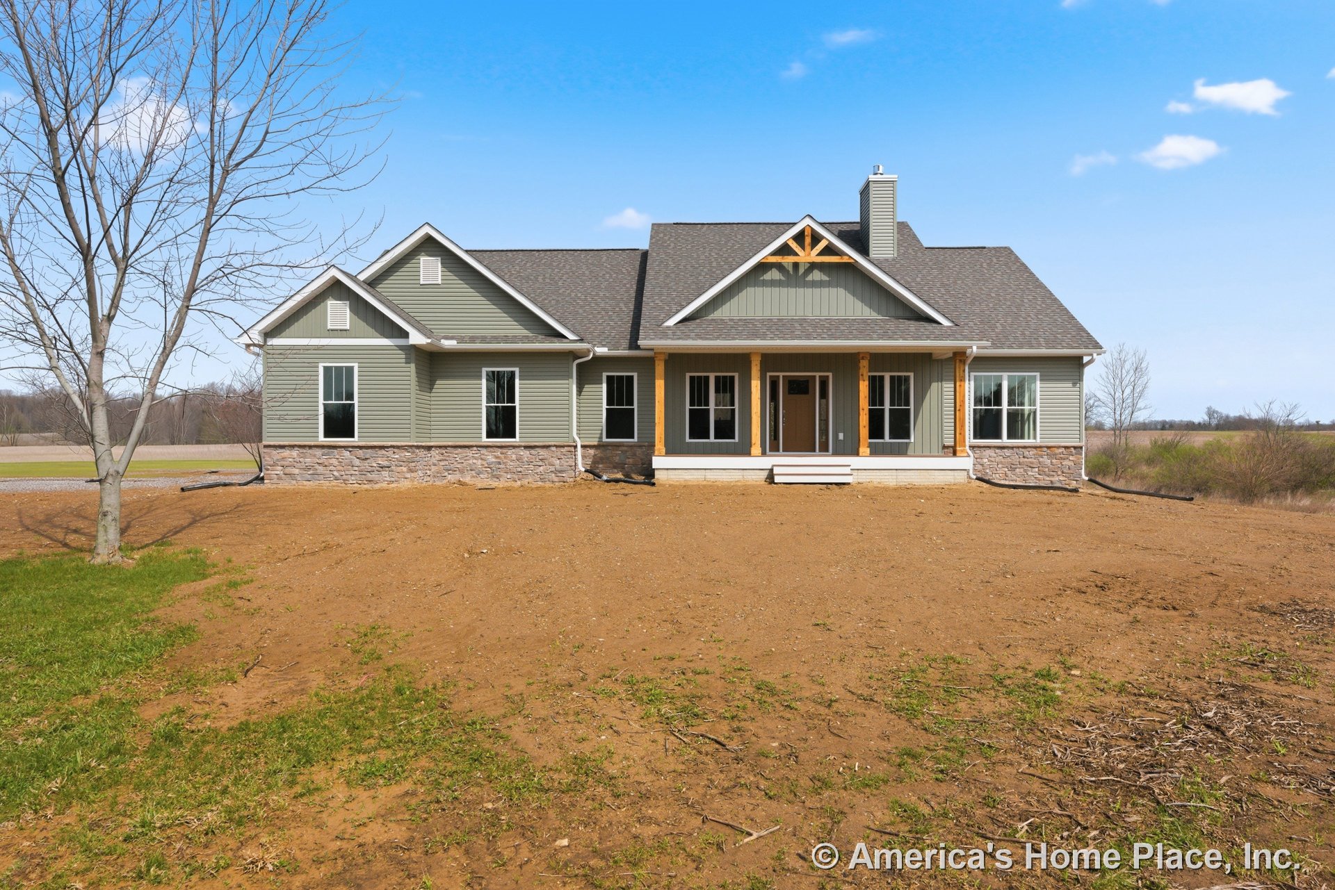 Covered front porch with wood columns, stone veneer base, lap siding exterior, gable roof, multiple double-hung windows, and prominent entry door.