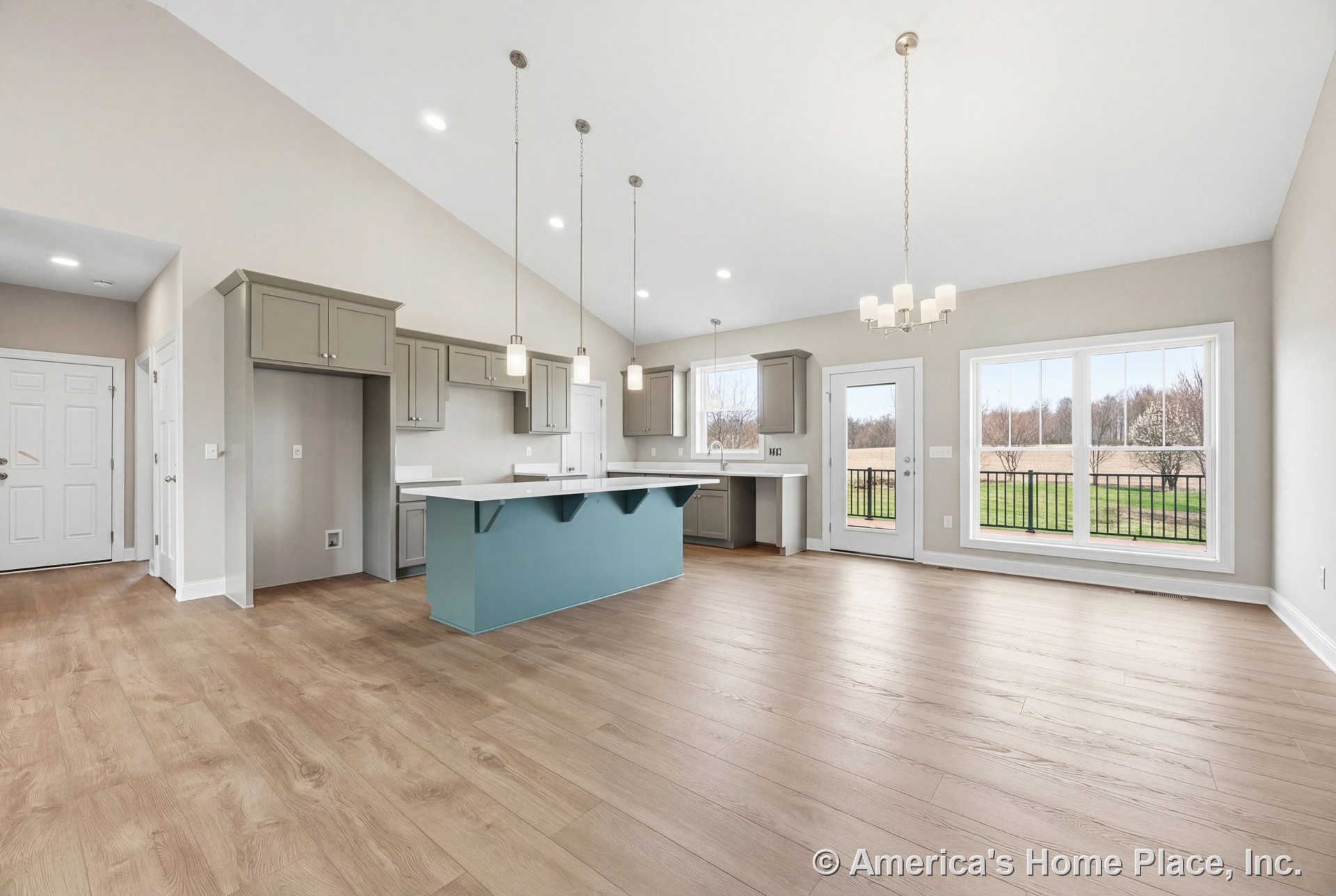 Open concept kitchen and dining area with vaulted ceiling, recessed lighting, large windows with white trim, light wood flooring, gray shaker cabinets, white quartz countertops