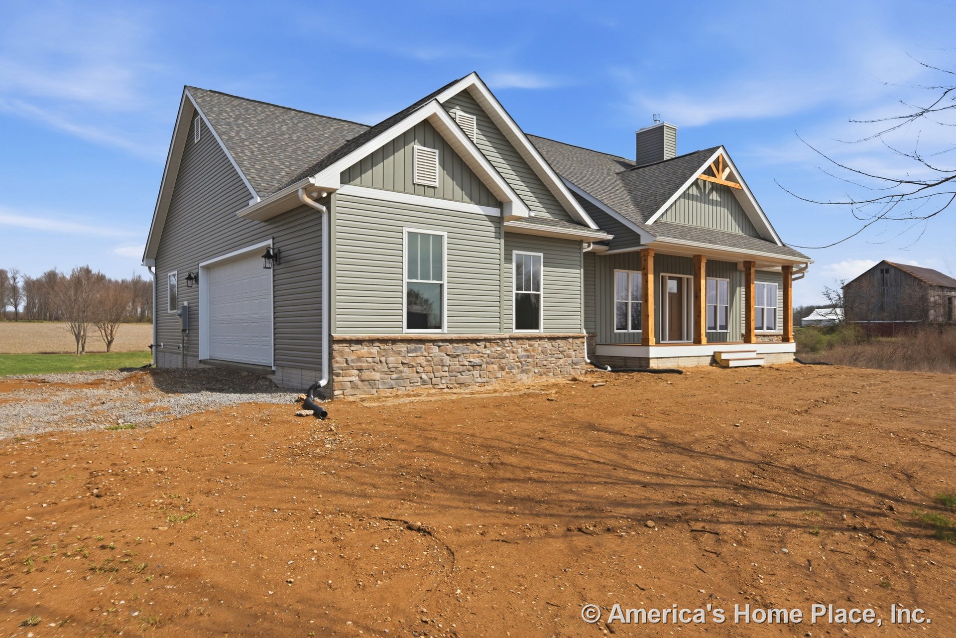Gray vinyl siding and stone veneer foundation with a covered front porch supported by wood columns, white trim and gutters, attached garage door, multi-pane windows, and front
