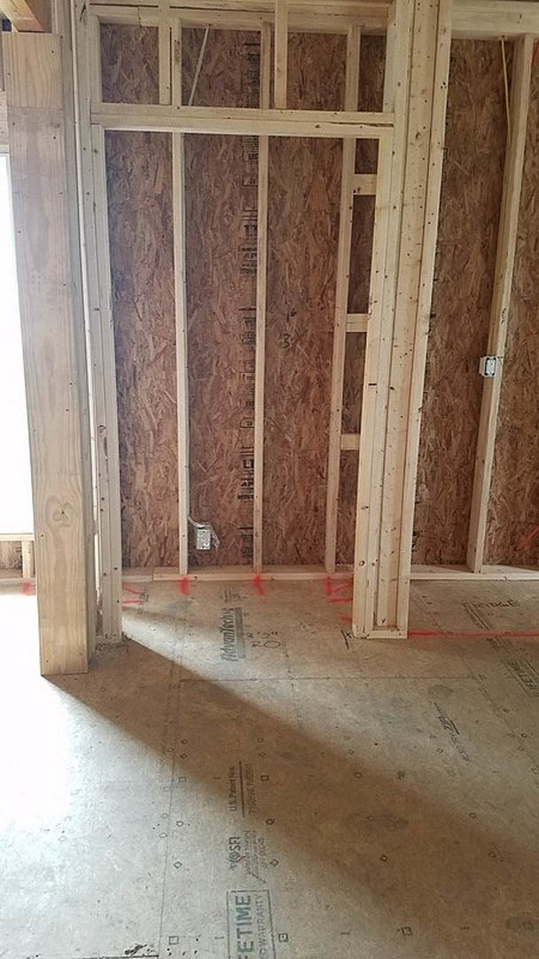 Exposed wood framing with beams and planks, unfinished walls, visible insulation, and plaster in a residential interior under construction