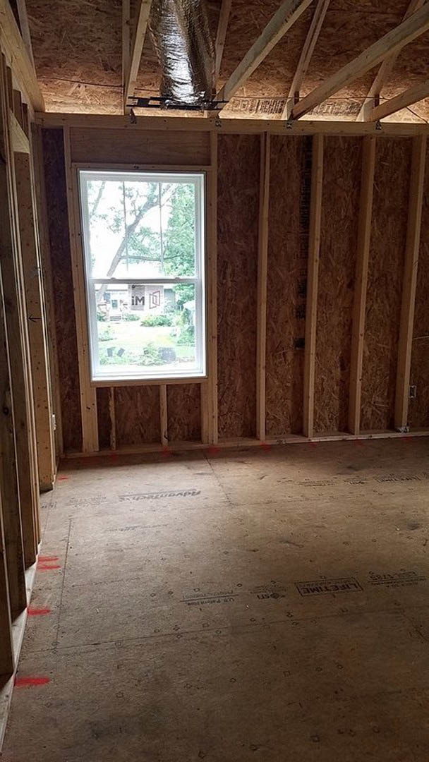 Large window set in a room with exposed wood ceiling beams, light-colored walls, and hardwood flooring.