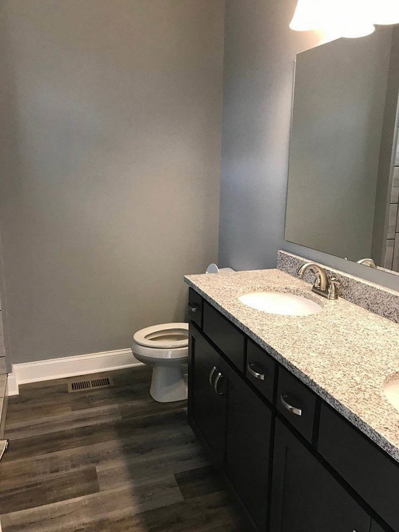 Marble countertop vanity with undermount sink, chrome faucet, white toilet, light-colored tile flooring, and white walls with black trim