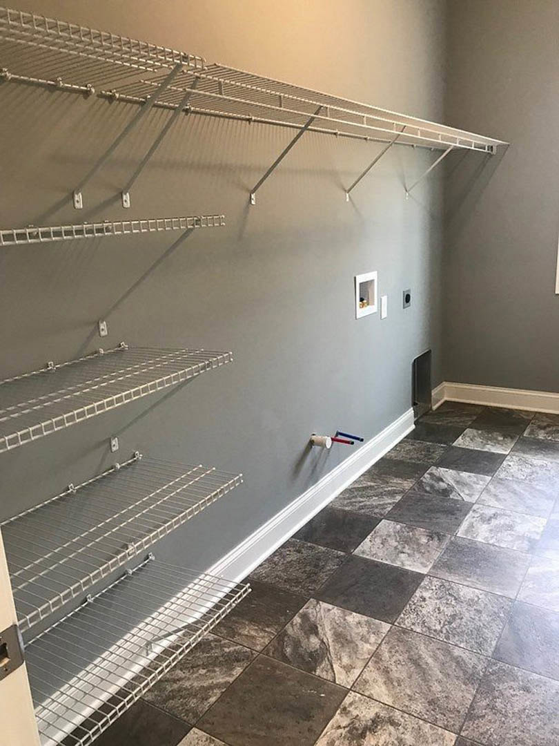 Tile floor room with wire metal shelving mounted on plaster wall, aluminum rack, and composite stone finishes
