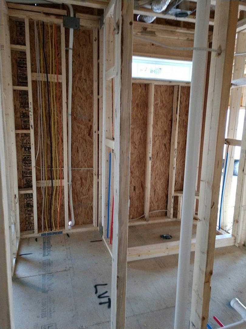 Unfinished room with exposed electrical wires, wooden beams, window, and white insulation panels