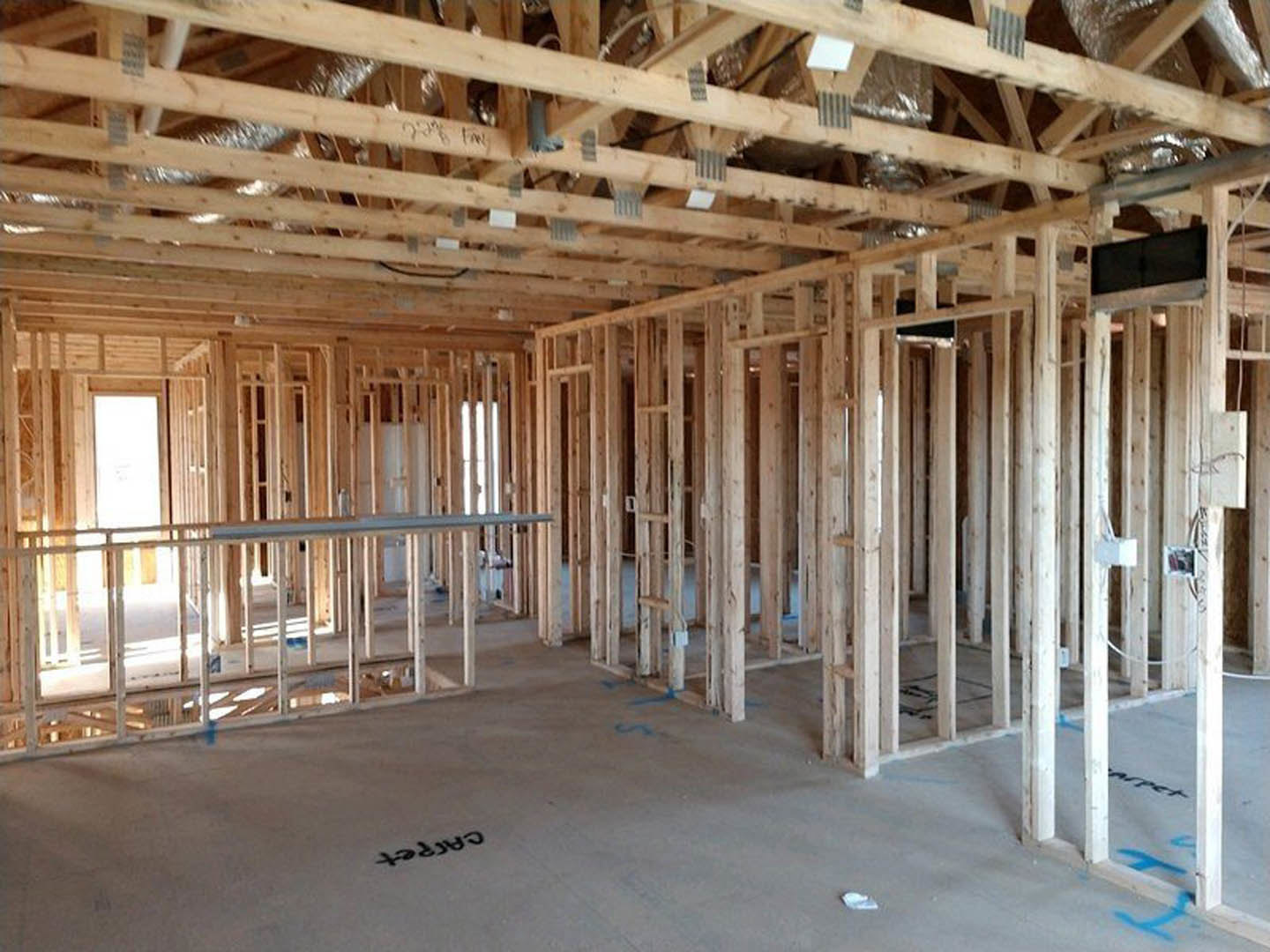 Exposed wooden beams and ceiling insulation inside a partially constructed residential home