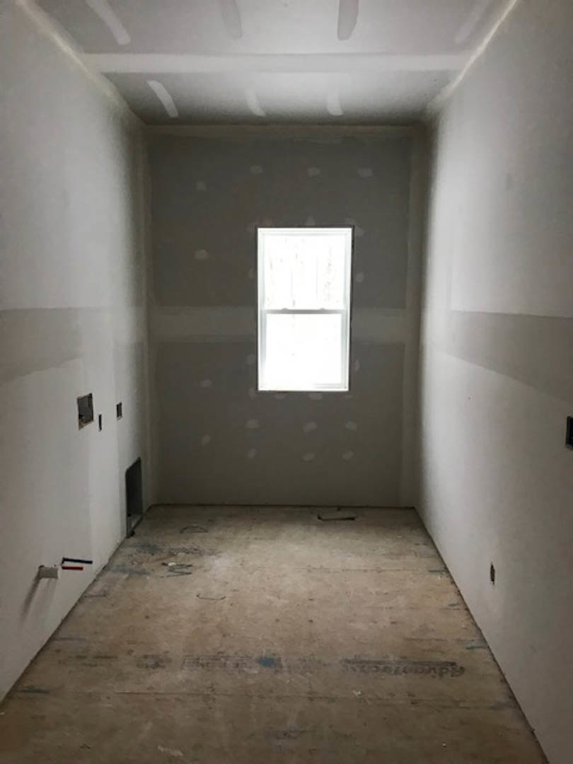 Concrete floor and white plaster walls in a room featuring a window with a white frame and black hinge.