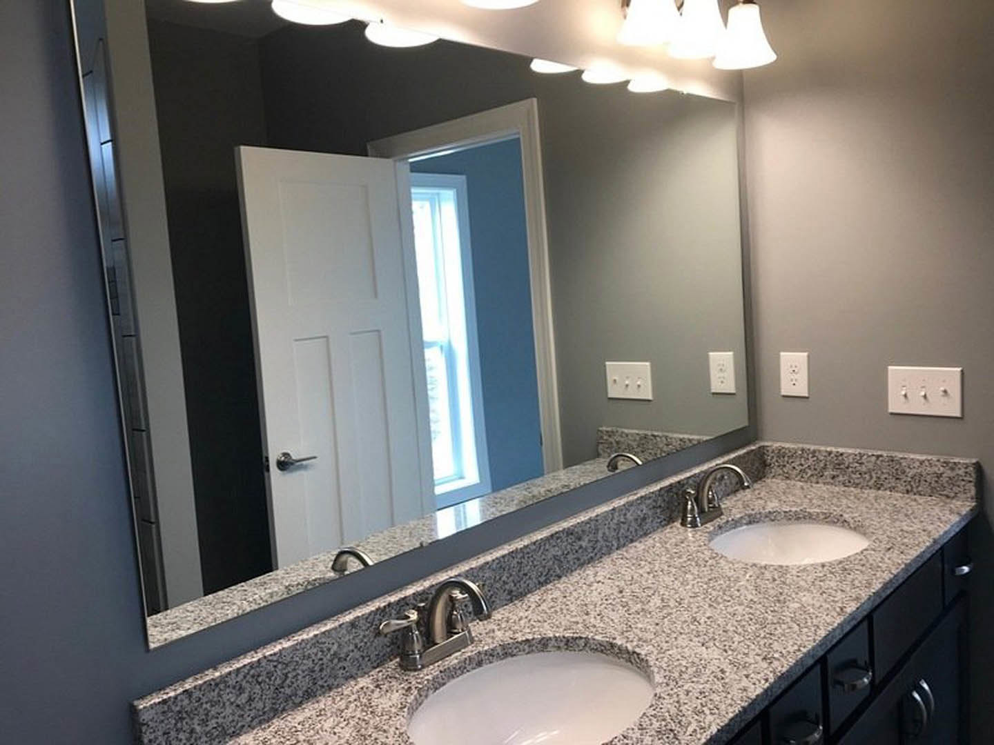 Modern bathroom featuring a wide framed mirror above a rectangular sink with chrome faucet, light-colored tile walls, and minimalist fixtures.