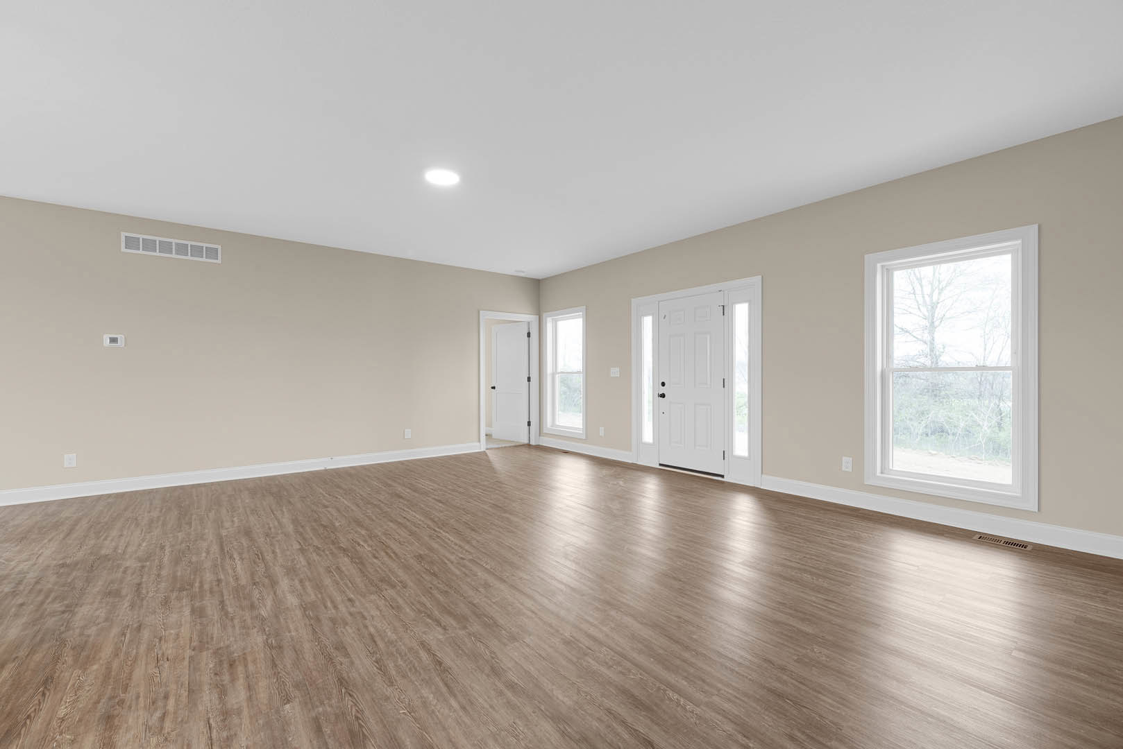Room with white walls, white doors featuring black handles and glass panels, hardwood floor, large window overlooking trees
