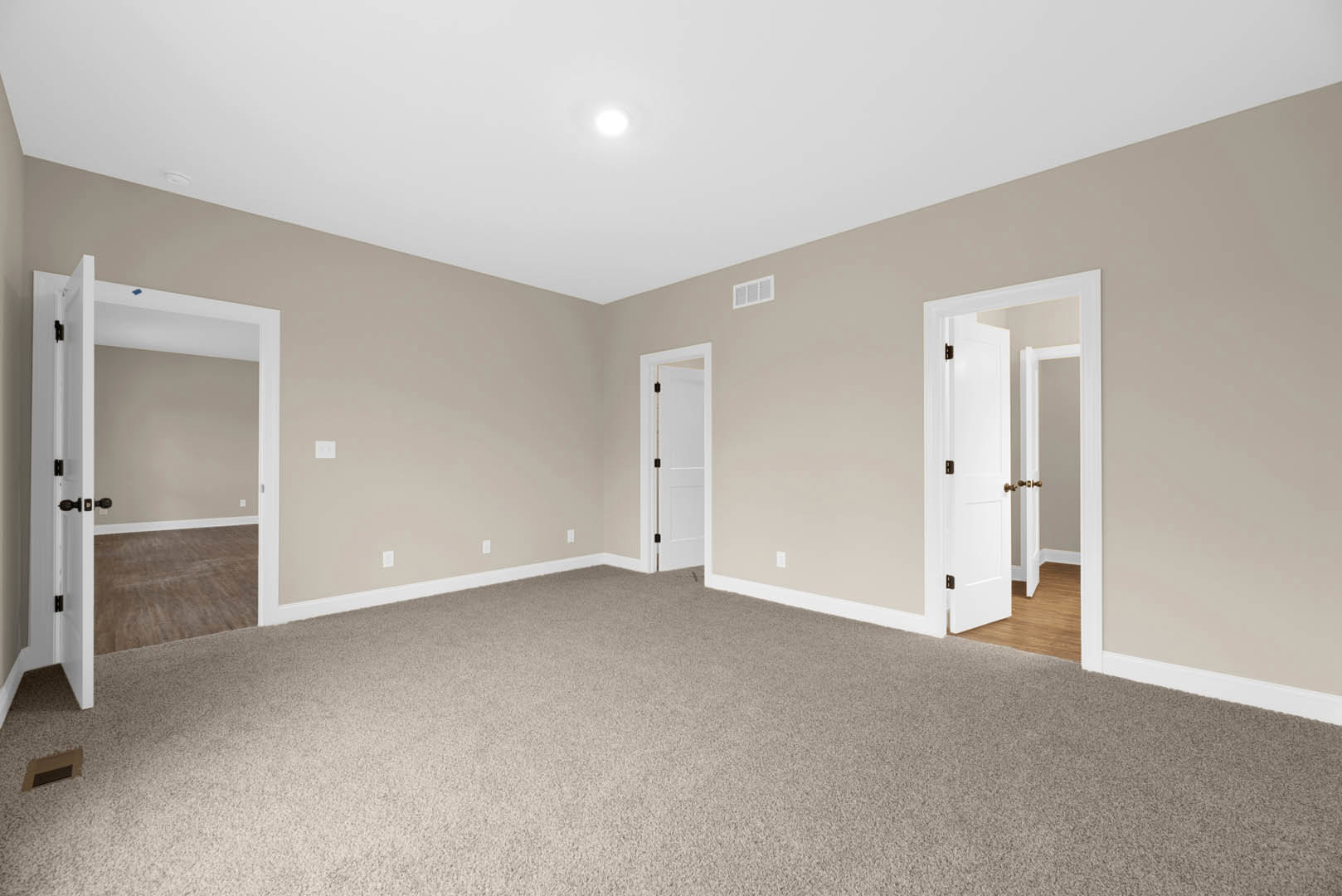 Beige walls with white baseboards and trim, white paneled door featuring a black handle and mirrored inset, light-colored carpet flooring, smooth plaster ceiling