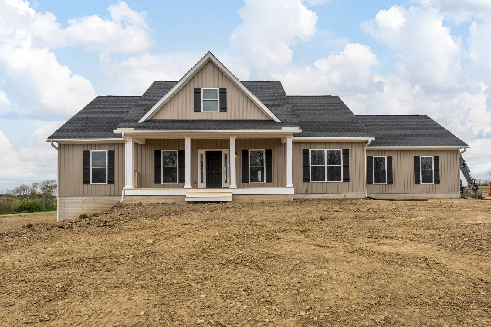White exterior wall and black roof house with glass-paneled black door, white-framed window, dirt hill in foreground, and tree visible through window