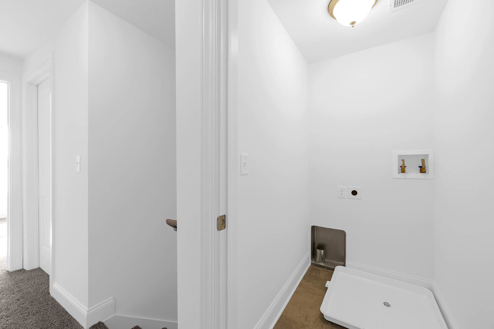 White hallway with plaster walls, open door, light fixture on ceiling, and smooth flooring