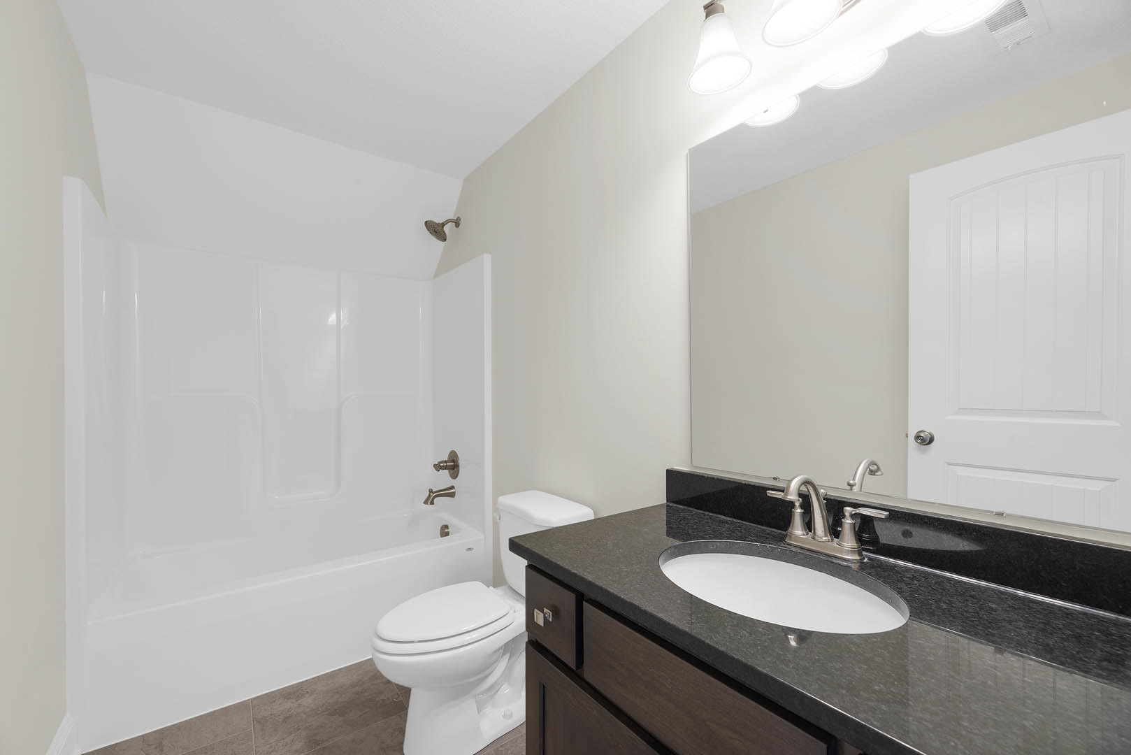 White tile bathroom featuring a freestanding bathtub, modern sink with chrome faucet, white toilet, and a paneled door with silver handle