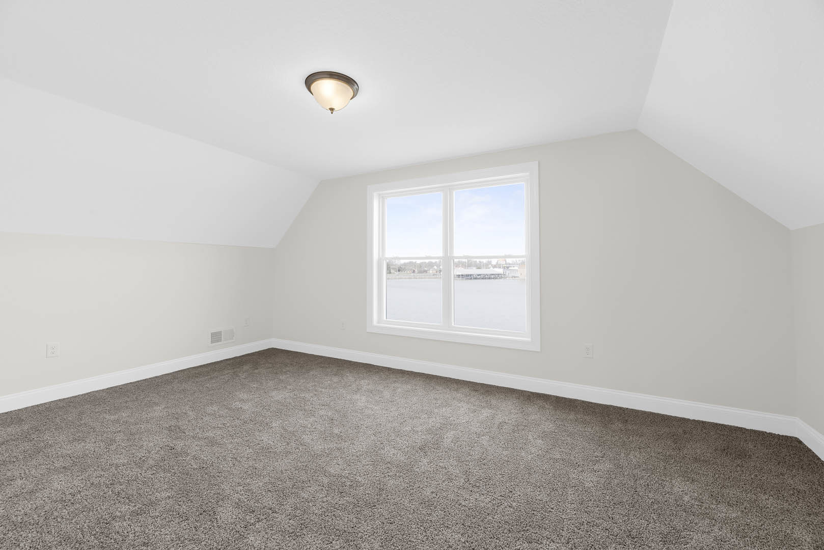 Carpeted room with white walls, large window overlooking water and city skyline, ceiling light fixture, wood trim molding