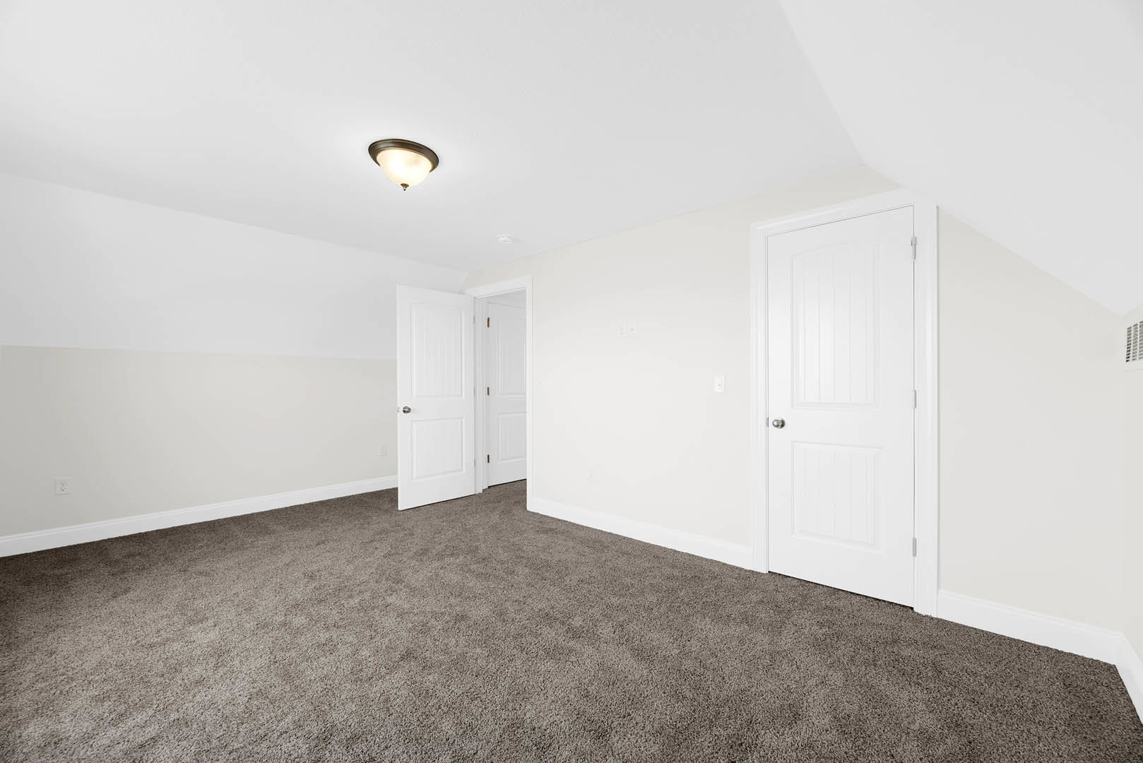 White-walled room with plush light carpet, white door featuring a silver handle, and modern ceiling light fixture