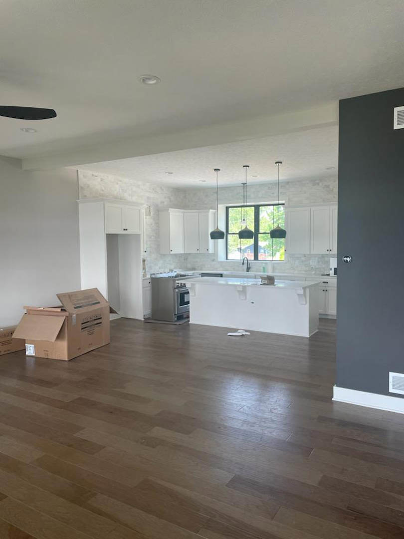 Kitchen with white island, wood flooring, stainless steel appliances, white cabinetry, and light walls