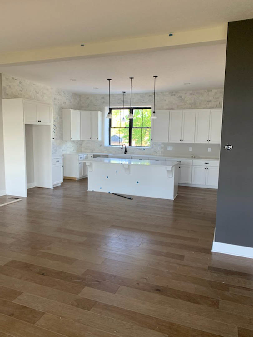 Kitchen featuring a white island with waterfall countertop, light wood flooring, white cabinetry, and recessed lighting