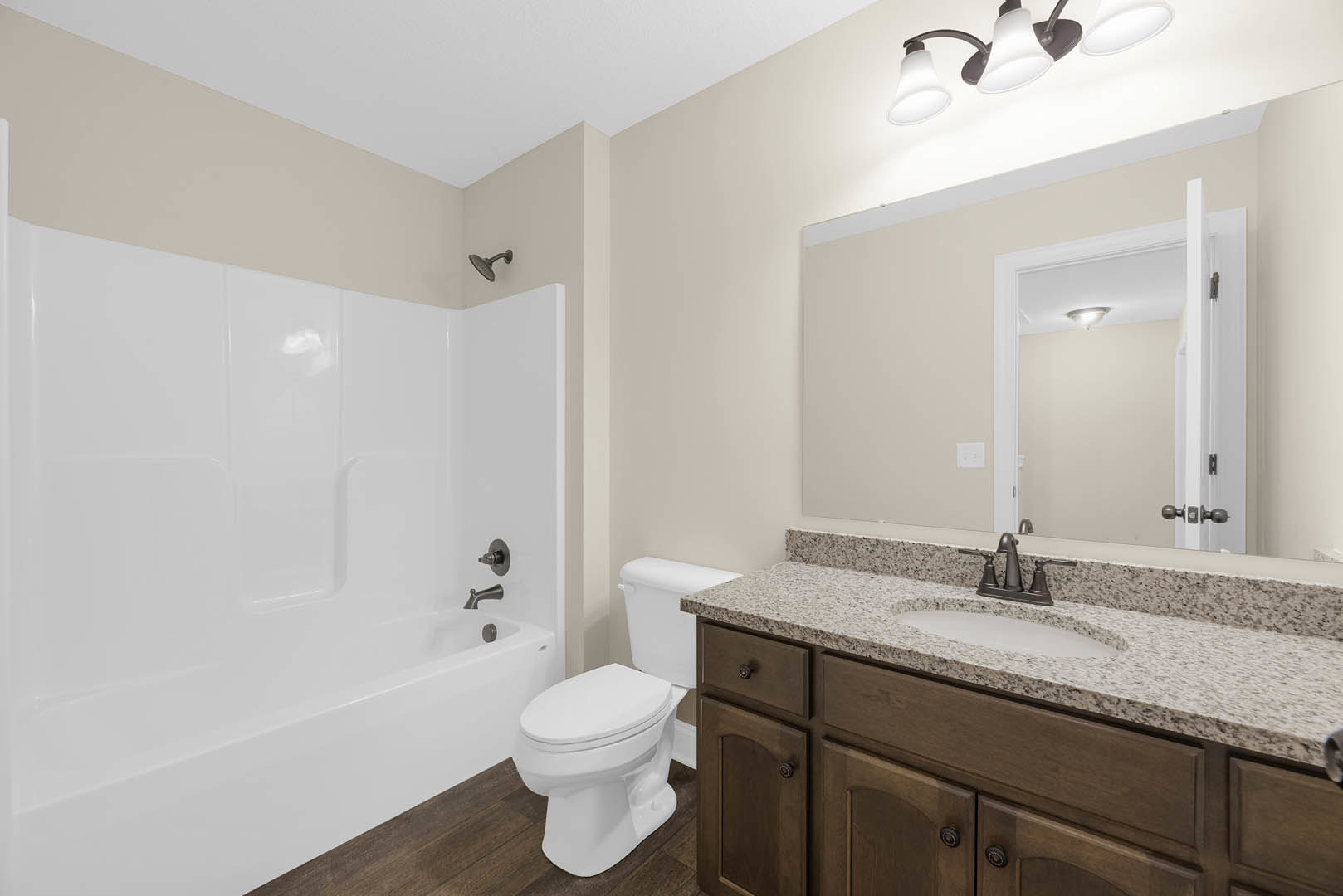 Modern bathroom featuring a freestanding white bathtub, rectangular sink with chrome faucet, white toilet, light gray tile walls, and a close-up of a brushed metal knob and