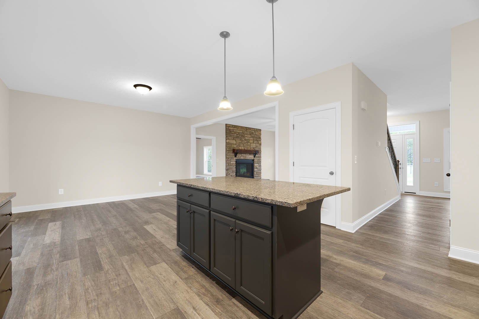 Granite kitchen island with built-in sink, white cabinetry, tile flooring, and large window in brick wall.