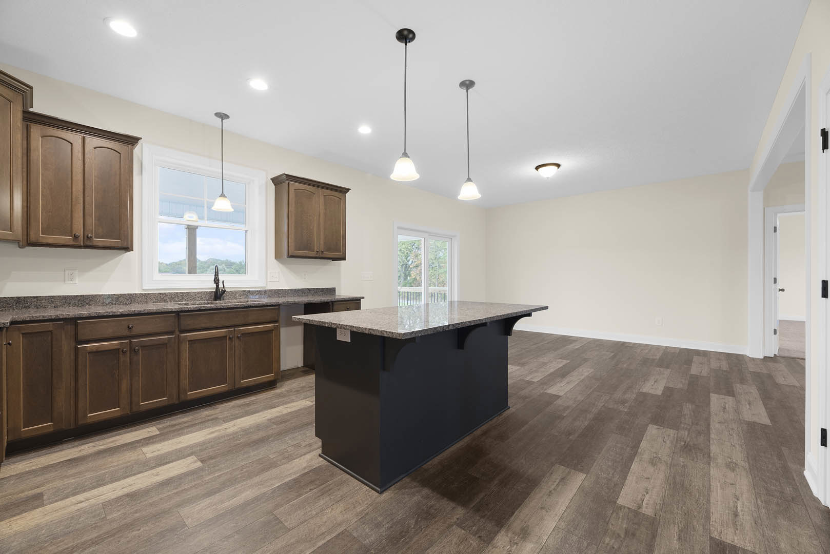 Kitchen featuring a marble-topped island, black countertops, wood flooring, white-framed window, and cabinetry with drawers and cupboards