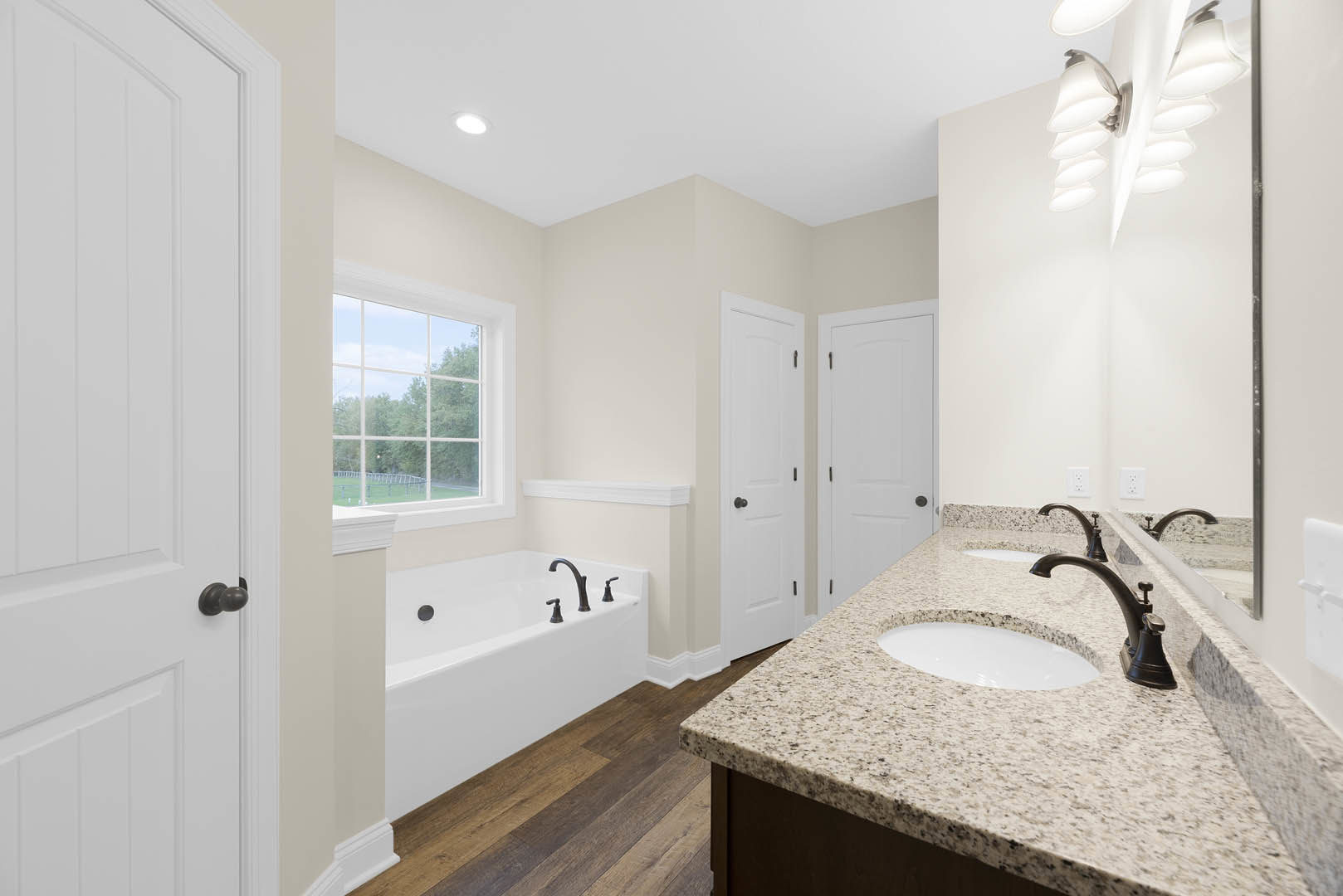 Marble countertop with white sink, freestanding bathtub, multi-pane window, ceiling light, and white door in a tiled bathroom