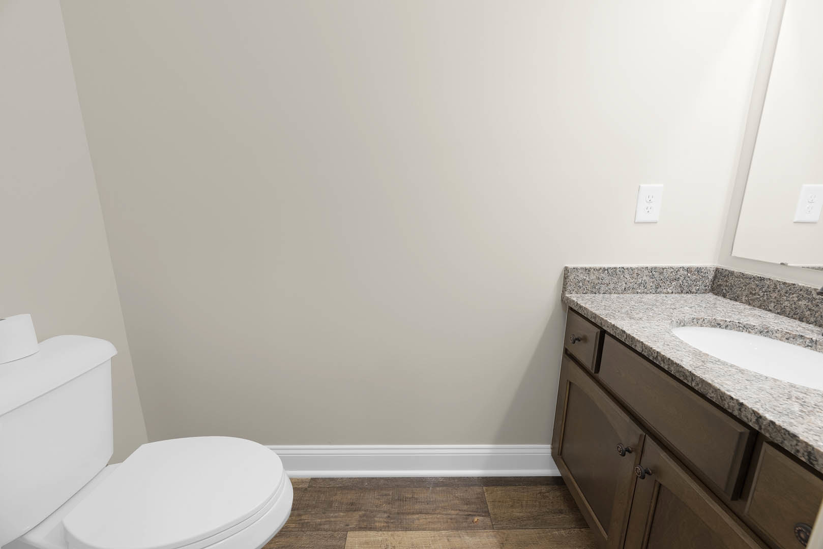 Bathroom with marble countertop, undermount sink, chrome faucet, white toilet, and light-colored tile walls