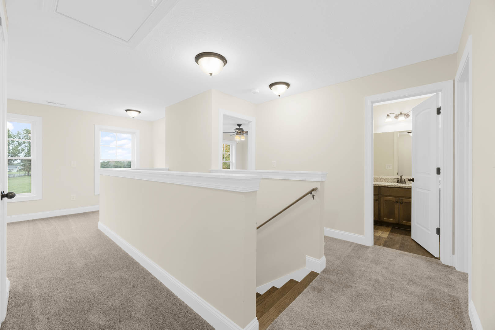 Wide hallway with light wood flooring, white plaster walls, and crown molding; staircase with wooden steps and white balusters; ceiling-mounted light fixture; door with glass